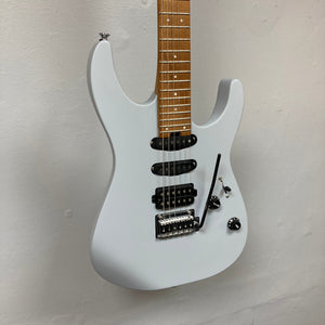 A gray Charvel DK24 HSS 2PT CM electric guitar by Charvel, featuring black pickups, a whammy bar, and two control knobs, shown against a plain white wall.