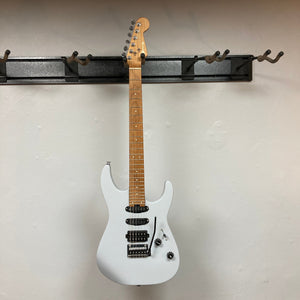 A used Charvel DK24 HSS 2PT CM Electric Guitar in gray with a maple neck and fretboard hangs on a black wall-mounted rack, featuring three Seymour Duncan pickups, a whammy bar, and two control knobs against an off-white background.