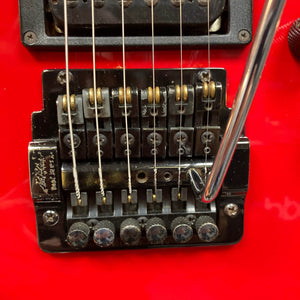 Close-up of a red Charvel Model 4 HSS electric guitar's black Floyd Rose tremolo bridge with six strings and a chrome whammy bar. Brand: Charvel. Product: Charvel Model 4 HSS Red w/OHSC Consign.