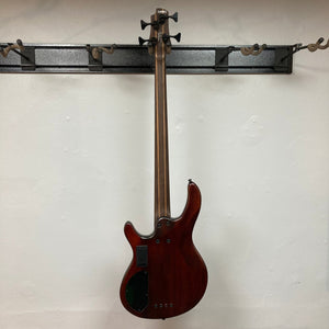 Cort Artisan B4 Element Burgundy Red bass guitar mounted on a wall, showcasing its ergonomic mahogany body and high-mass MetalCraft M4 bridge.