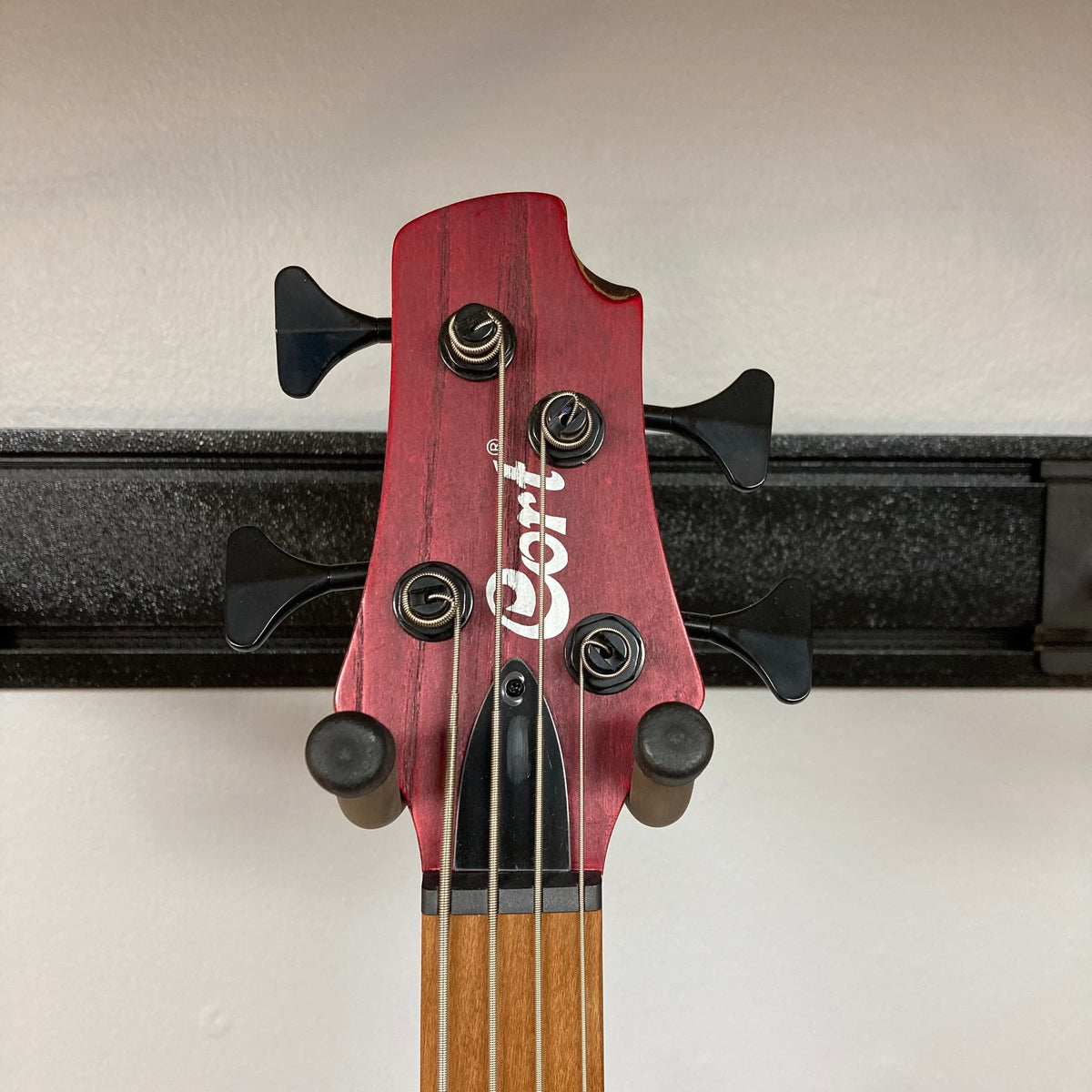 Close-up of the Cort Artisan B4 Element Burgundy Red guitar head featuring white text and strings, highlighting its craftsmanship and premium components.
