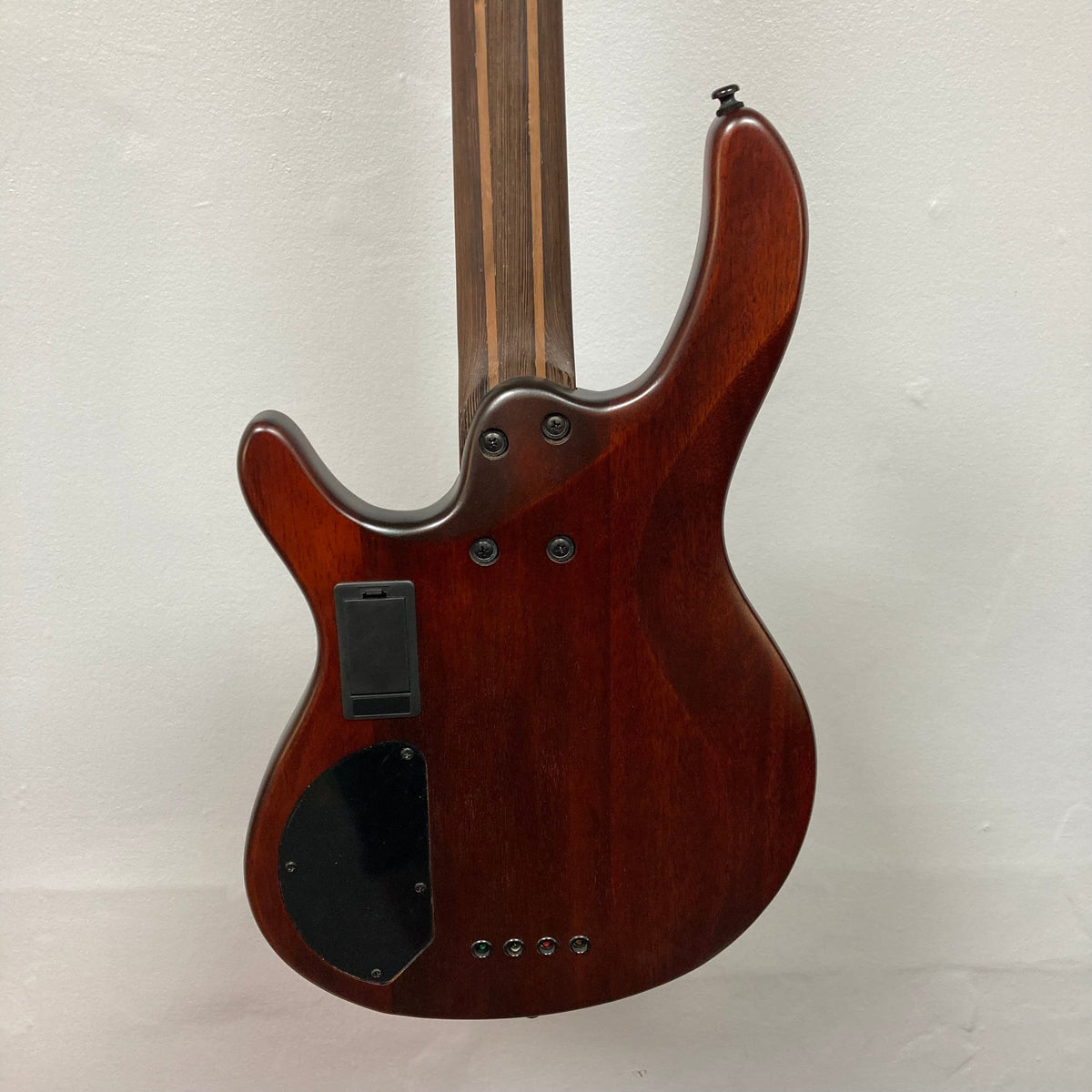 Close-up of a Cort Artisan B4 Element Burgundy Red bass guitar, highlighting its roasted maple fretboard, Bartolini MK-1 pickups, and ergonomic mahogany body.