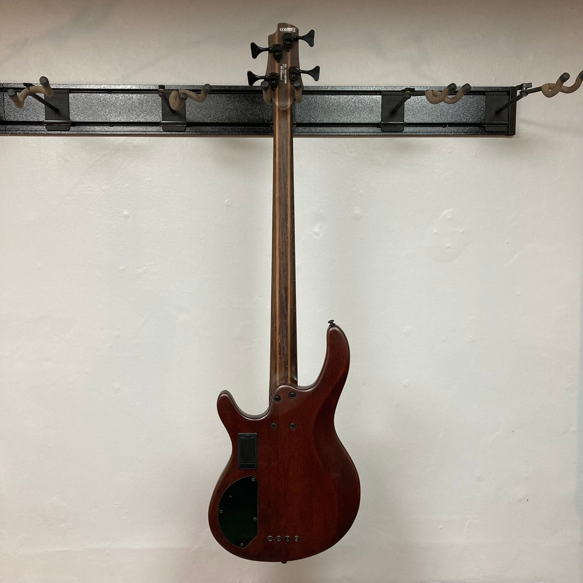 Cort Artisan B4 Element Natural bass guitar with roasted maple fretboard, Bartolini pickups, and ergonomic mahogany body, showcased against a wall.
