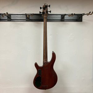 Cort Artisan B4 Element Natural bass guitar with roasted maple fretboard, Bartolini pickups, and ergonomic mahogany body, showcased against a wall.
