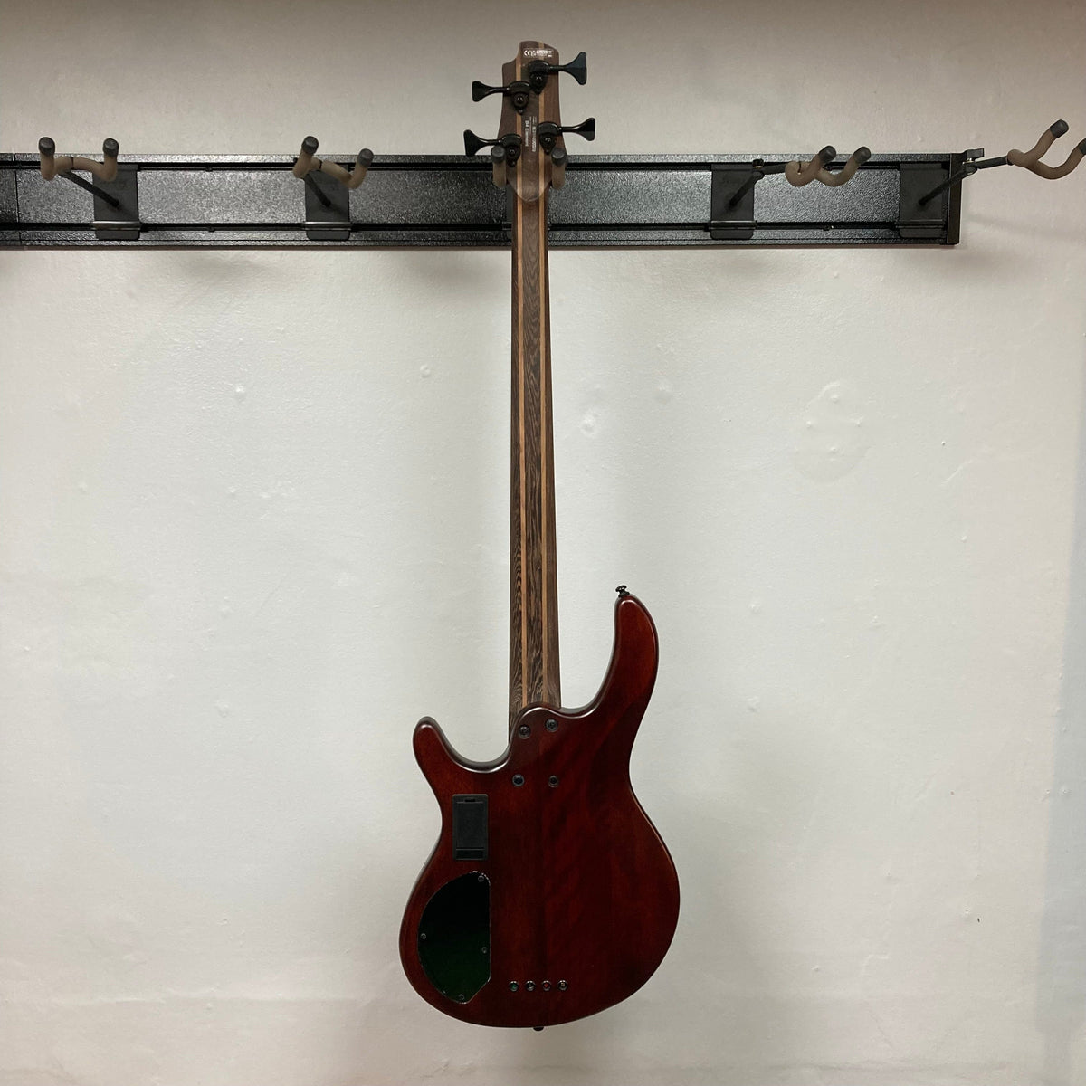 Cort Artisan B4 Element Open Pore Black bass guitar with Bartolini pickups, 5-piece neck, and MetalCraft M4 bridge hanging on a wall.