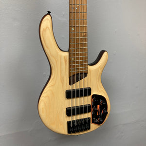 Cort Artisan B5 Element Natural Used bass guitar on wall, highlighting its roasted maple fretboard and ergonomic body, with visible Bartolini pickups and MetalCraft M5 bridges.