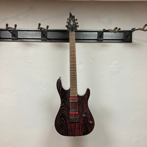 Cort KX300 EBR Etched Black Red electric guitar with ash top and EMG® RetroActive Super77 humbuckers, displayed on a wall.