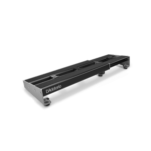 A D'Addario XPND Expanding Pedalboard by D'Addario, featuring a sleek black rectangular metal frame and four rubber feet, is displayed at an angle on a plain white background.