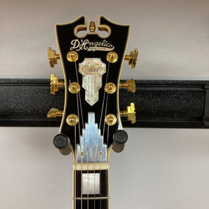 D'Angelico Excel DC Semi-hollowbody Vintage Natural guitar on a stand, showcasing its double-cutaway design and semi-hollow construction with gold hardware.