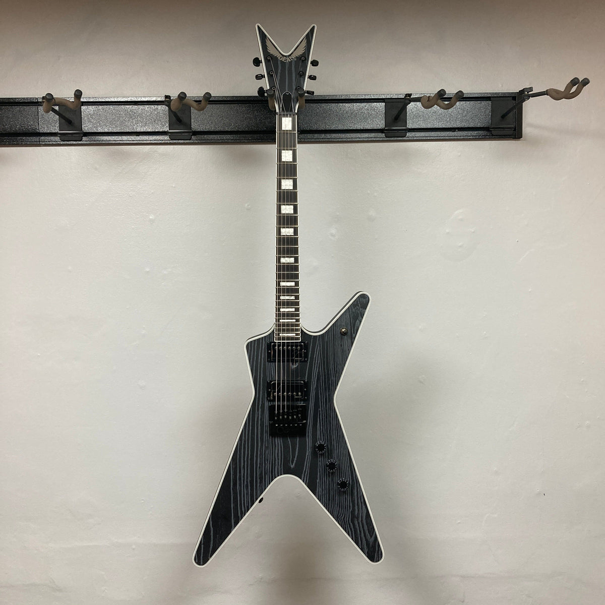 Dean Custom Run #16 ML Sandblasted Grey guitar on a hook, showcasing its distinctive design and craftsmanship, limited to 100 units with premium features.