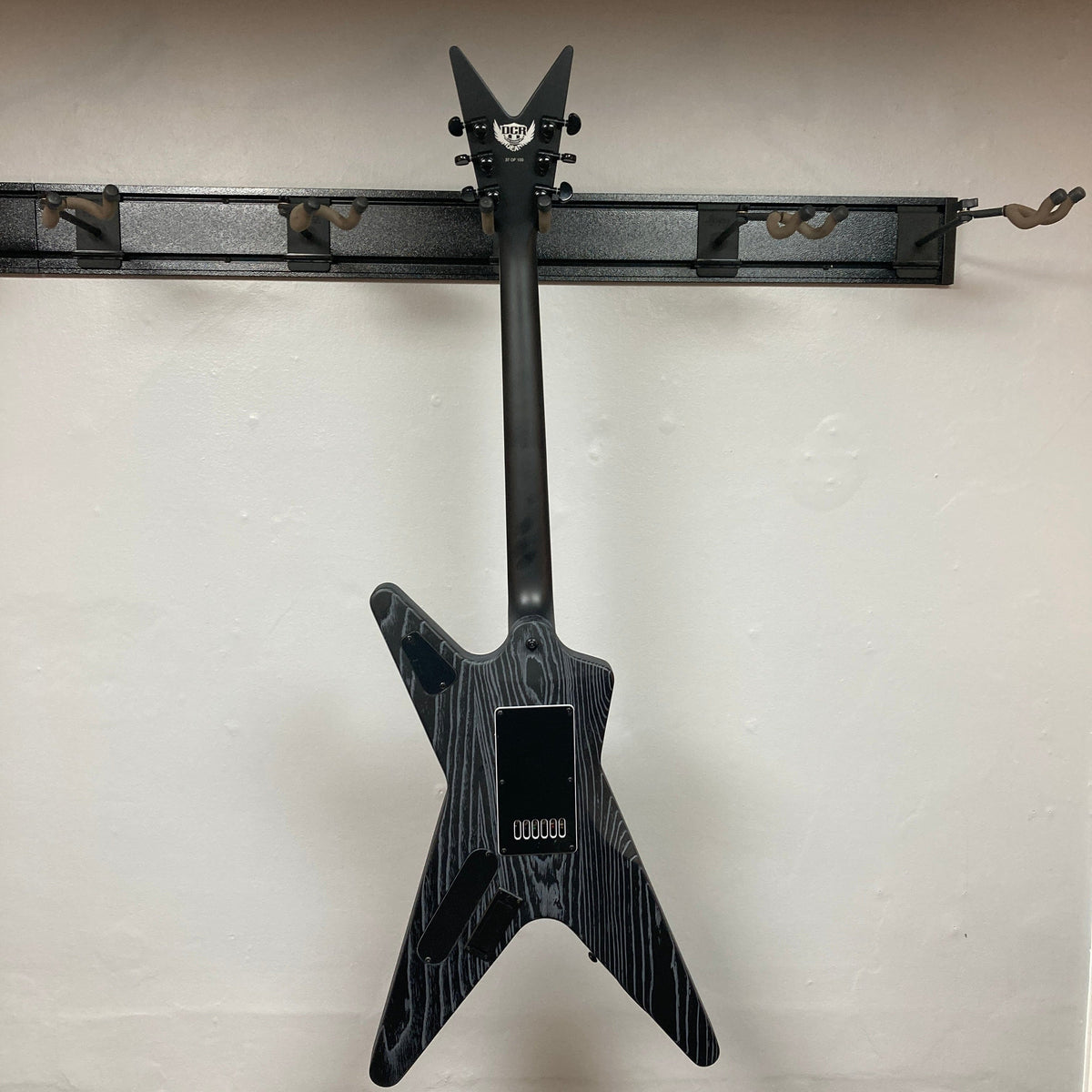 Dean Custom Run #16 ML guitar mounted on a wall, showcasing its unique sandblasted grey finish and iconic ML design.
