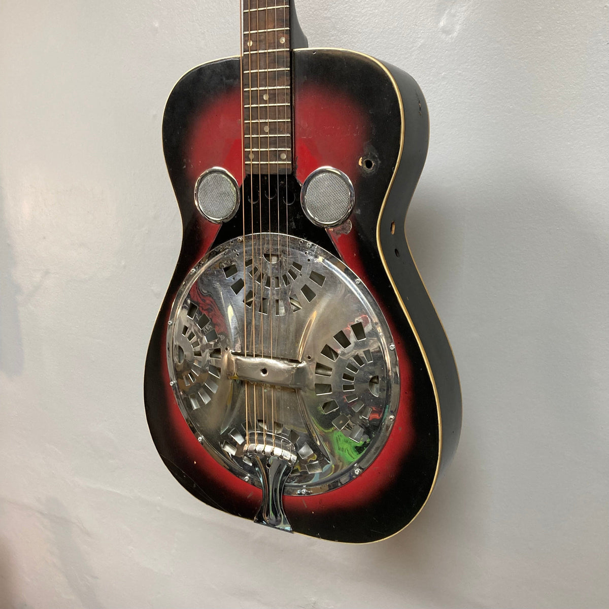 Dobro Model 60 DS Round Neck 1970s Red Burst resonator guitar, showcasing close-up of strings and metal resonator, highlighting its distinct traditional design and used condition.