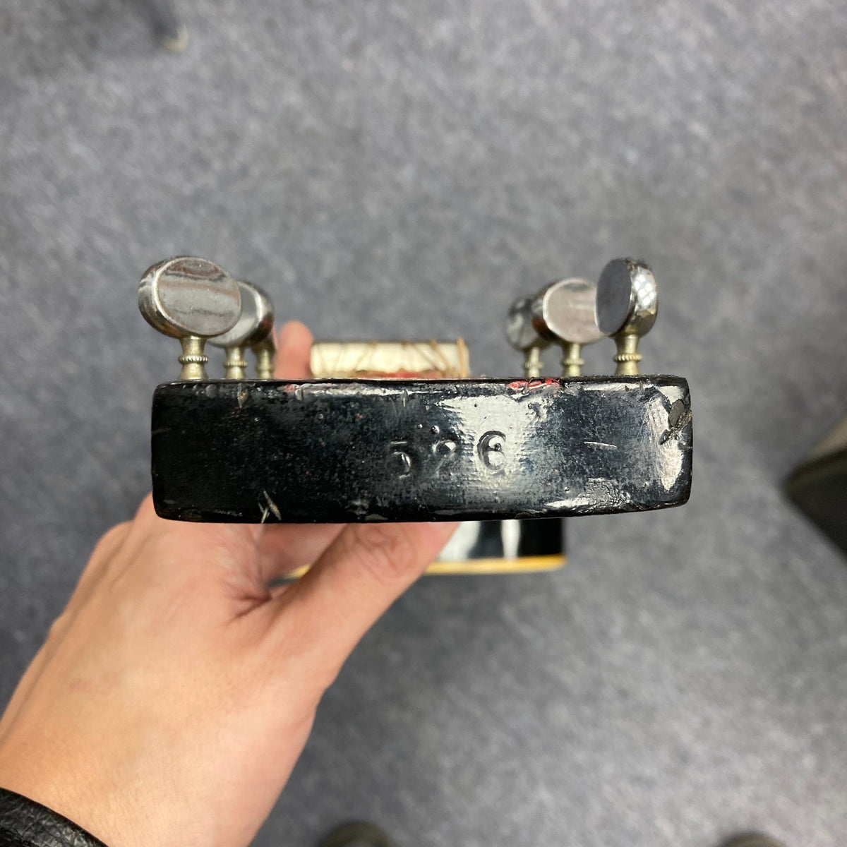 Hand gripping a Dobro Model 60 DS Round Neck 1970s Red Burst resonator guitar, showing silver knobs and metal details.