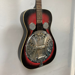 Dobro Model 60 DS Round Neck 1970s Red Burst resonator guitar with metal cover and visible strings, showing wear from use.