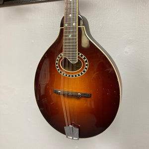 Eastman MD604-GB A-Style Oval-Hole Mandolin displayed on a wall, highlighting its intricate string design and craftsmanship, perfect for musicians. Case included.