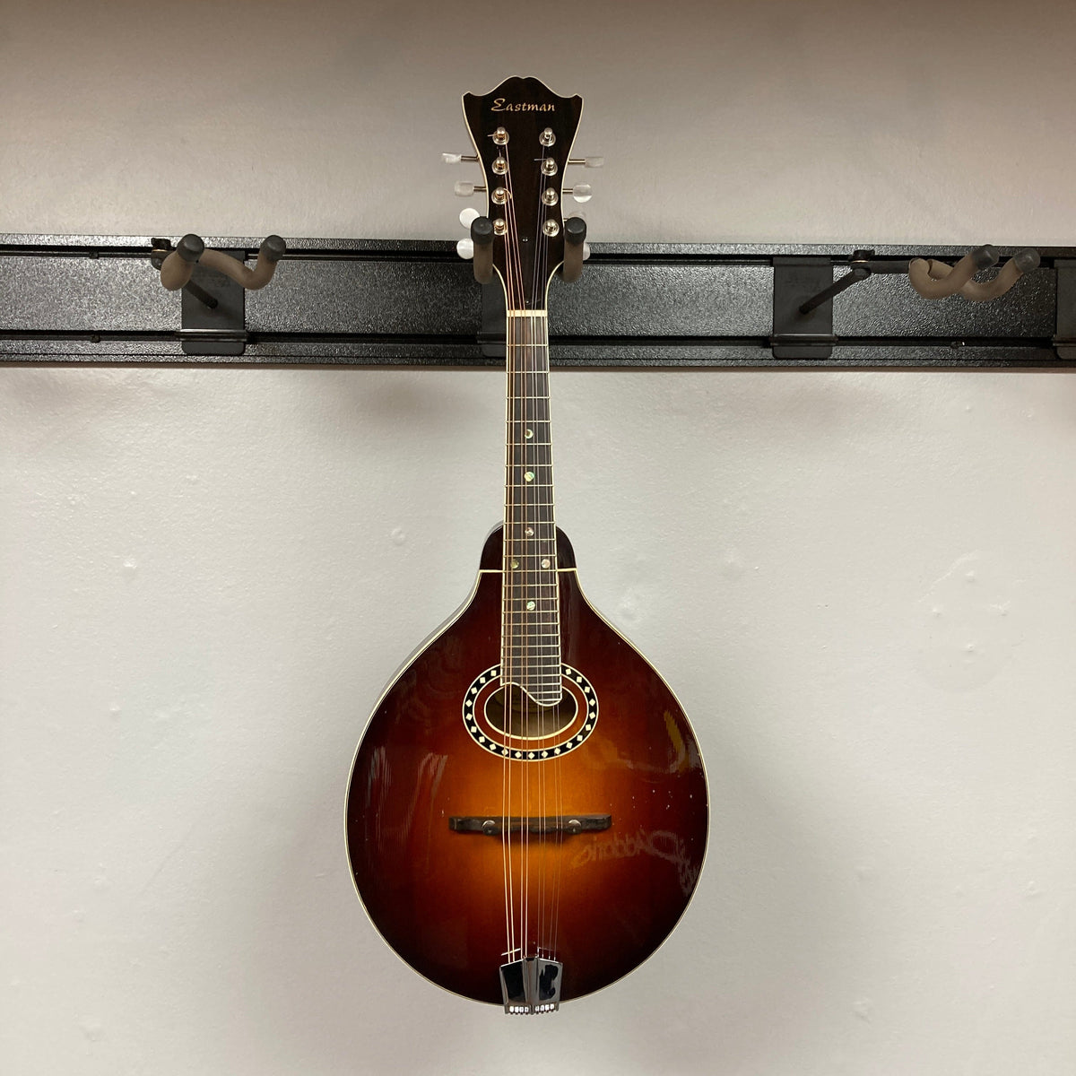 Eastman MD604-GB A-Style Oval-Hole Mandolin displayed on wall, highlighting its craftsmanship and design. Case included, perfect for musicians seeking quality instruments.