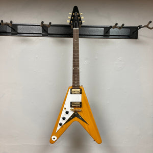 Epiphone 1958 Korina Flying V Left-handed guitar hanging on a hook, showcasing its distinctive design and craftsmanship, including the solid Korina body and Gibson pickups.