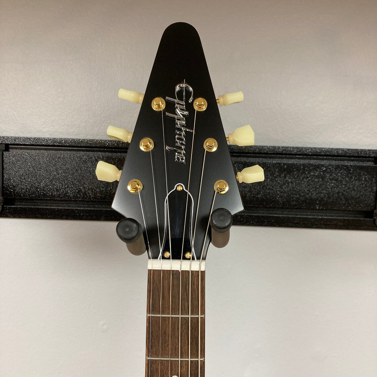 Epiphone 1958 Korina Flying V Left handed w/Case on stand, showcasing its solid Korina body and Indian laurel fretboard.