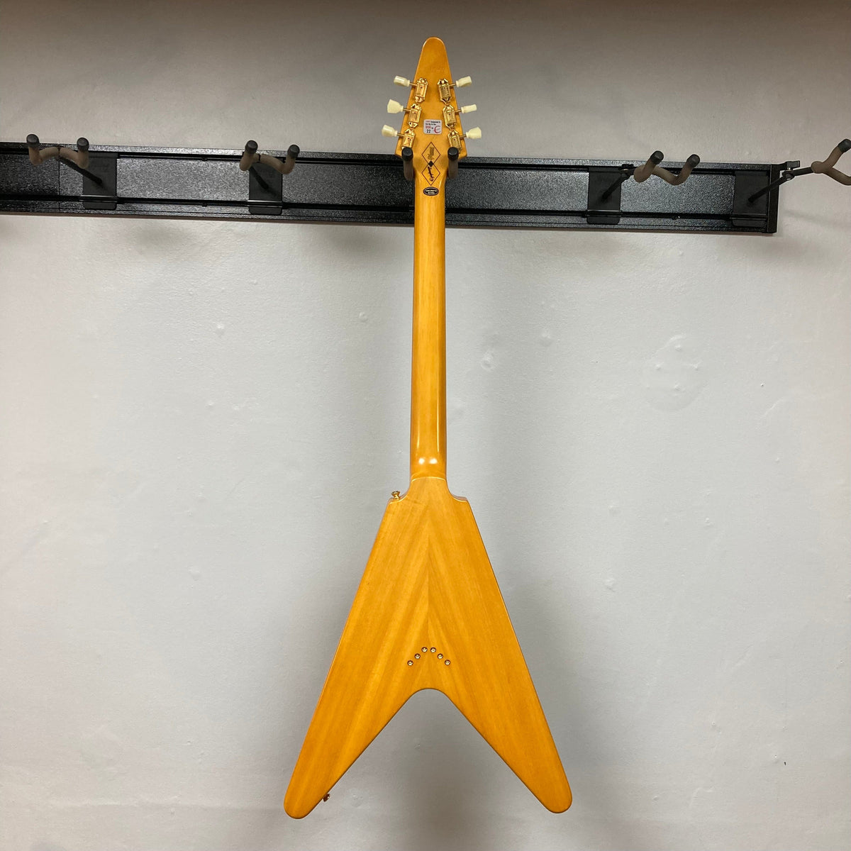 Epiphone 1958 Korina Flying V Left handed guitar mounted on a wall, showcasing its classic design and craftsmanship.
