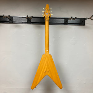Epiphone 1958 Korina Flying V Left handed guitar mounted on a wall, showcasing its classic design and craftsmanship.