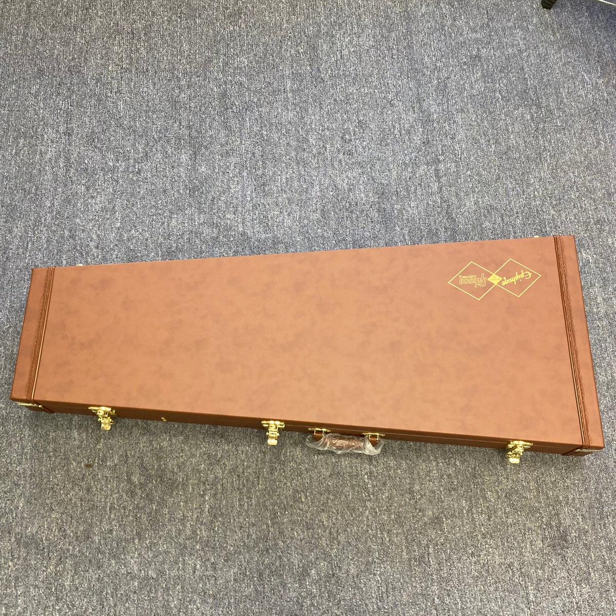 Epiphone 1958 Korina Flying V guitar in a brown hardshell case with gold handles.