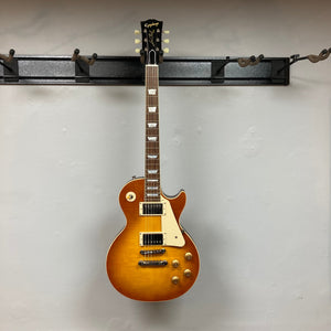Epiphone 1959 Les Paul Standard Iced Tea Inspired by Gibson, featuring a mahogany body, maple top, and Custombucker humbucking pickups, mounted on a wall.