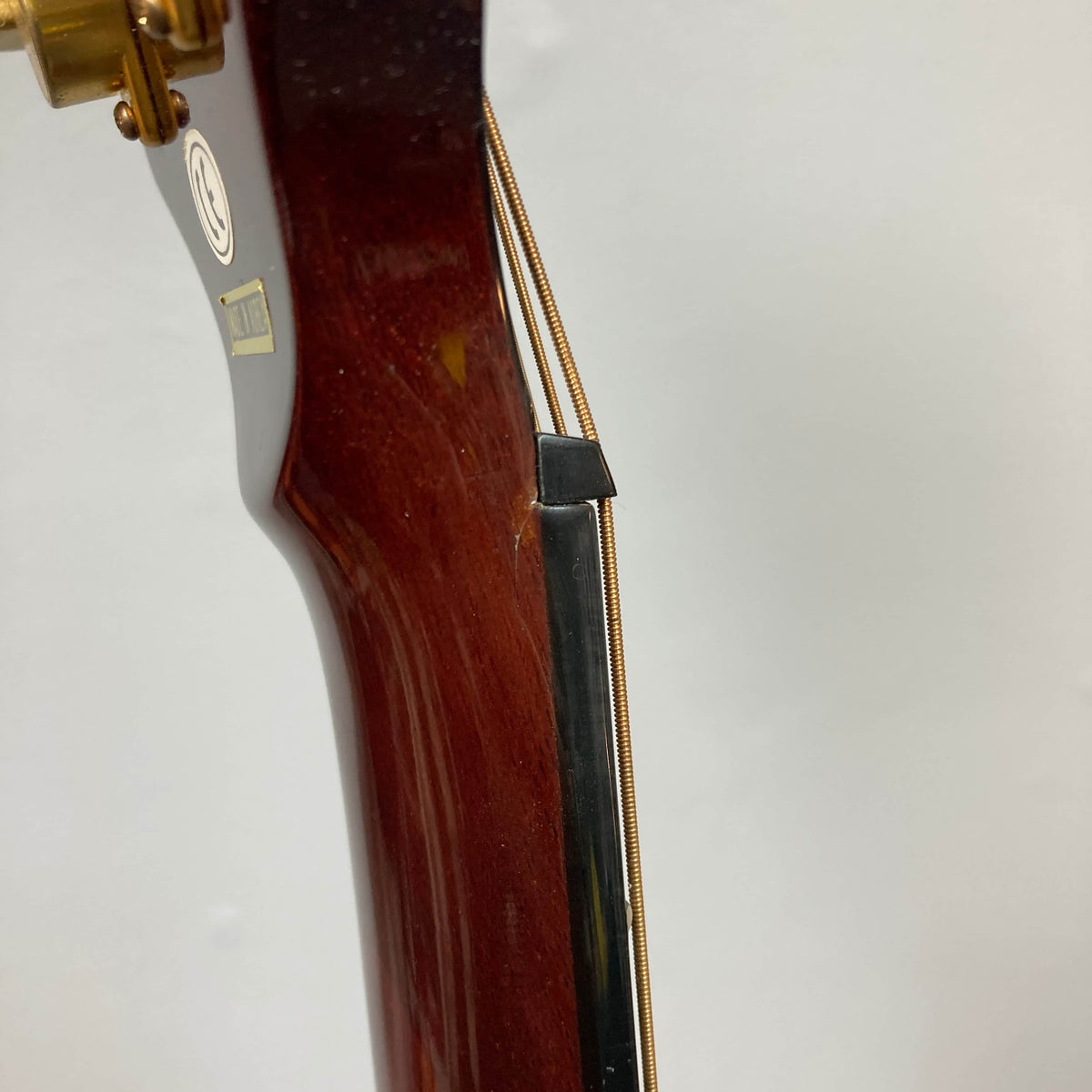 Close-up of an Epiphone Chet Atkins SST Studio Natural Korea headstock with a broken neck and visible crack, guitar strings intact—highlighting durability challenges of this feedback-resistant Epiphone acoustic-electric, used consignment with hard case.