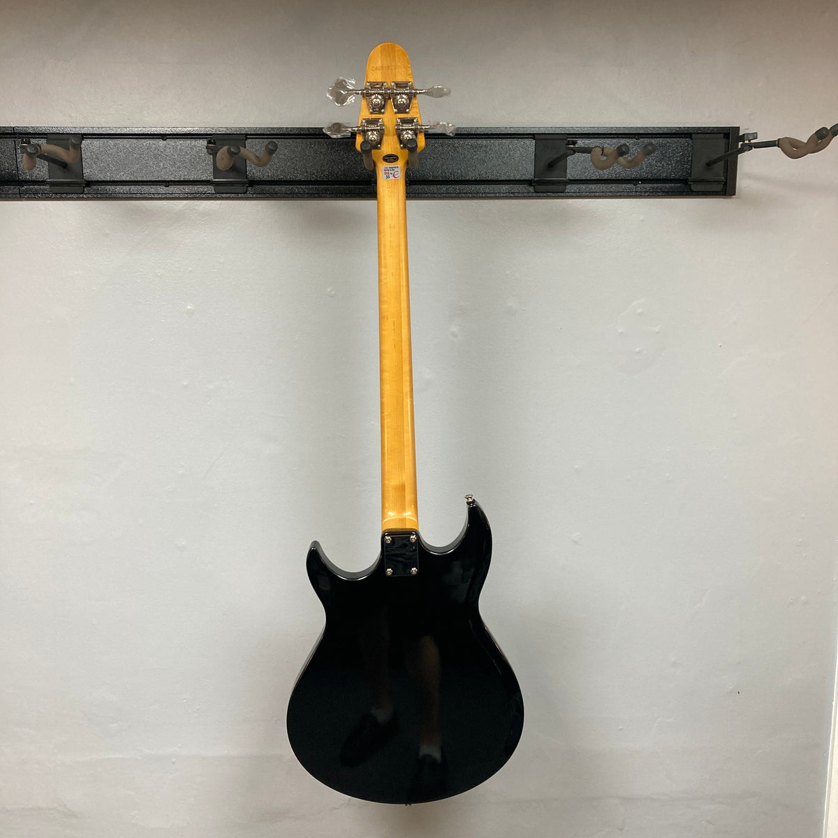 Epiphone Grabber Bass Ebony displayed on wall, showcasing sleek alder body, bolt-on maple neck, and solid hardware, ideal for versatile rock performances.