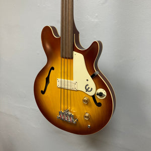 Epiphone Jack Casady Fretless Bass - Aged Royal Tan, displayed on a wall, showcasing its archtop body and iconic design features.