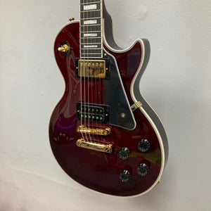 Epiphone Jerry Cantrell Wino Les Paul Custom Wine Red guitar displayed on a wall, featuring gold hardware and custom details.