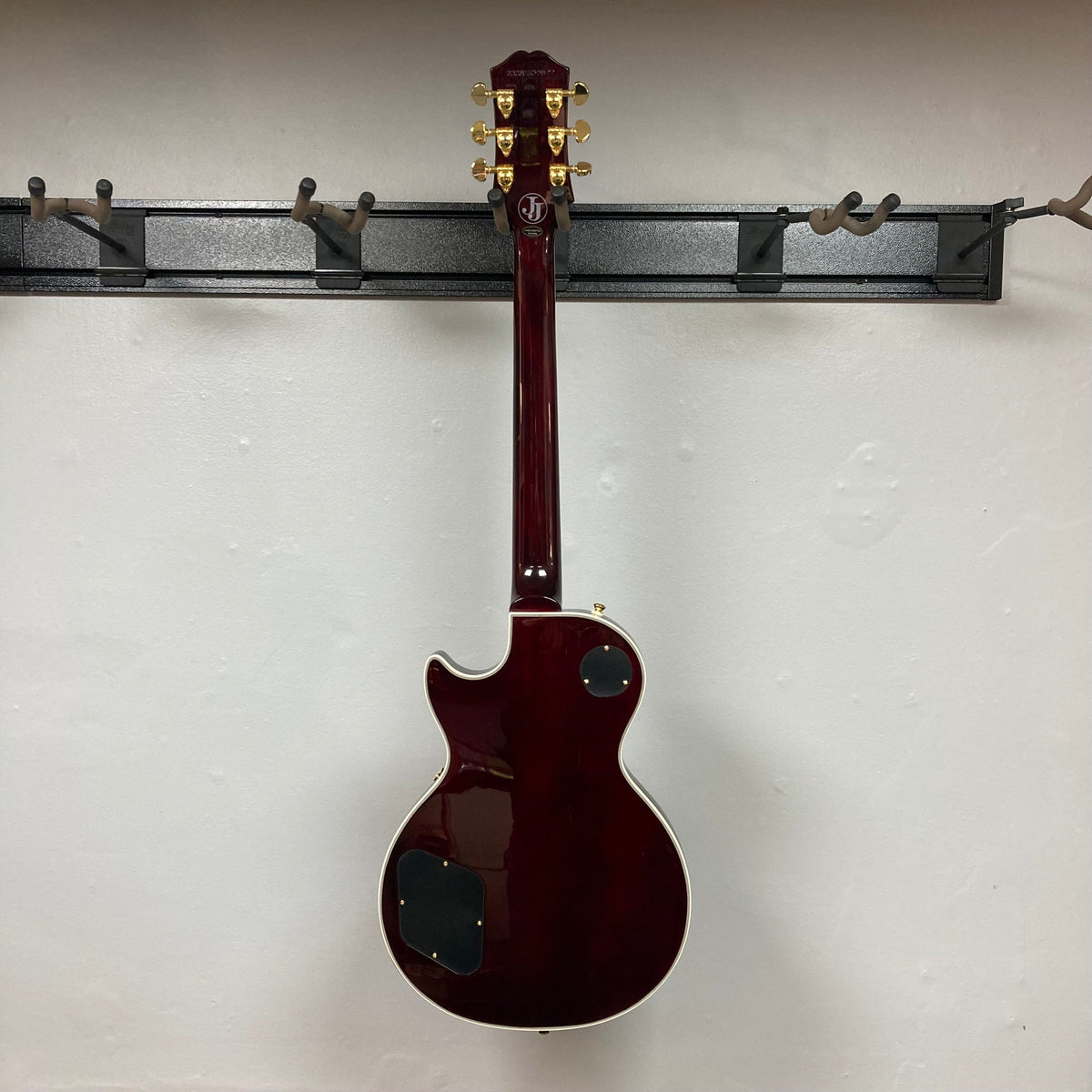 Epiphone Jerry Cantrell Wino Les Paul Custom Wine Red guitar displayed on a wall, showcasing its elegant design and craftsmanship.