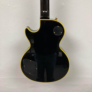 Epiphone Joe Bonamassa 59 Les Paul Custom Bigsby, glossy black with cream binding, rear cavity covers, and strap button, reflecting premium craftsmanship.