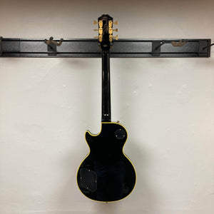 Epiphone Joe Bonamassa 59 Les Paul Custom Bigsby displayed from the rear on a wall-mount rack, showcasing its classic shape and craftsmanship.