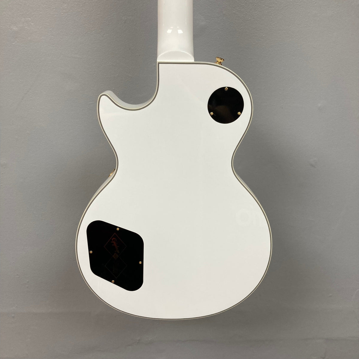 Epiphone Les Paul Custom Inspired by Gibson Alpine White guitar with black dots, gold hardware, and ebony fretboard, showcased with a hardshell case.