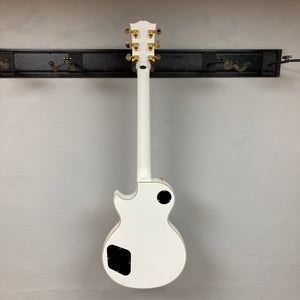 Epiphone Les Paul Custom Inspired by Gibson Alpine White guitar with gold hardware and black accents, displayed upright.