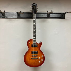 Epiphone Les Paul Modern Figured Mojave Burst electric guitar on a wall, highlighting its premium build and features, including ProBucker pickups and Grover Locking Rotomatic tuners.