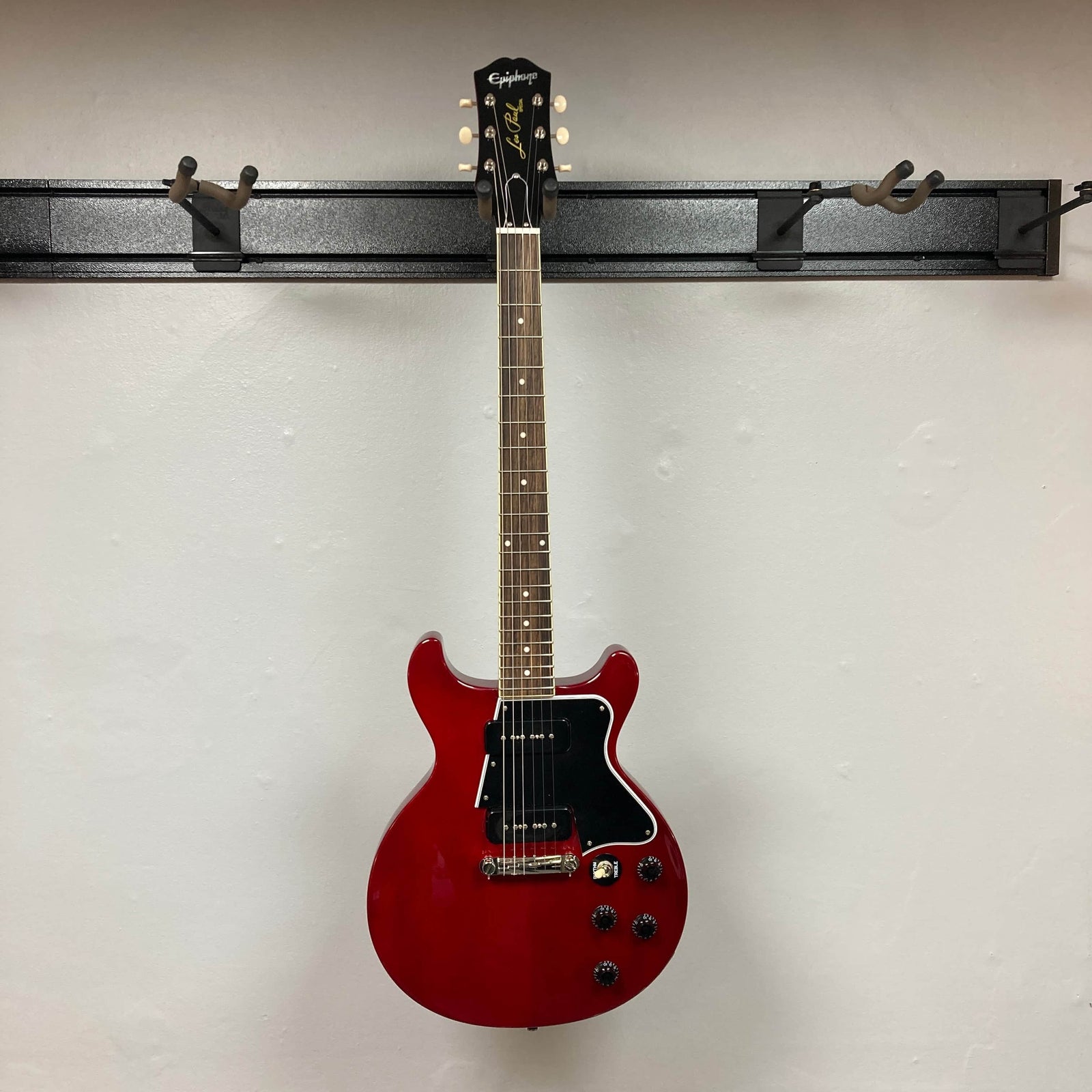 An Epiphone Les Paul Special Double Cut Cherry Red electric guitar with gigbag, featuring dual pickups, four control knobs, black pickguard, by Epiphone. Set against a plain light background. An Epiphone Les Paul Special Double Cut Cherry Red electric guitar with gigbag, featuring dual pickups, four control knobs, black pickguard, by Epiphone. Set against a plain light background.