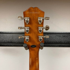 The back of an Epiphone Les Paul Standard 60s Ebony w/Gigbag guitar headstock with six metal tuning pegs is shown on a wall hanger against a white background.