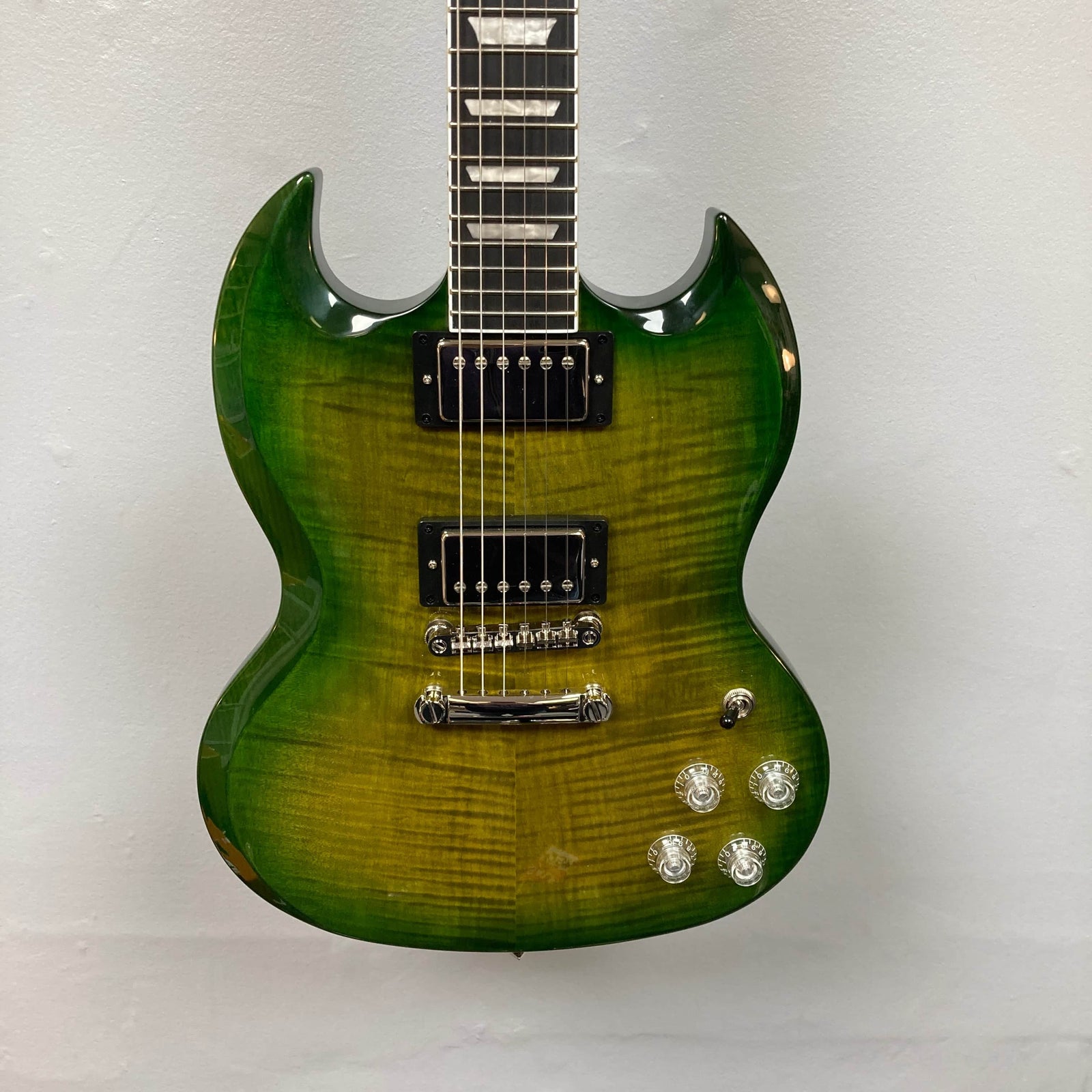 The Epiphone SG Modern Figured in Iguana Burst features a glossy finish, ProBucker humbuckers, four control knobs, a SlimTaper neck, and a double cutaway body—shown on a plain white background. Includes gig bag. The Epiphone SG Modern Figured in Iguana Burst features a glossy finish, ProBucker humbuckers, four control knobs, a SlimTaper neck, and a double cutaway body—shown on a plain white background. Includes gig bag.