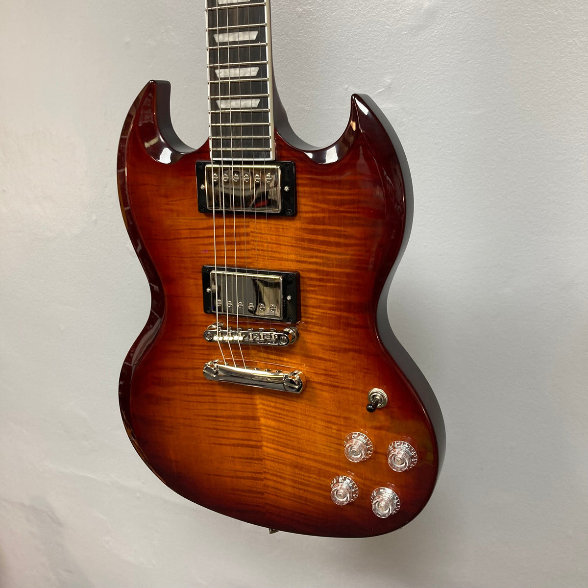 Epiphone SG Modern Figured Mojave Burst electric guitar with ProBucker pickups, ebony fingerboard, and Grover tuners, displayed on a wall.