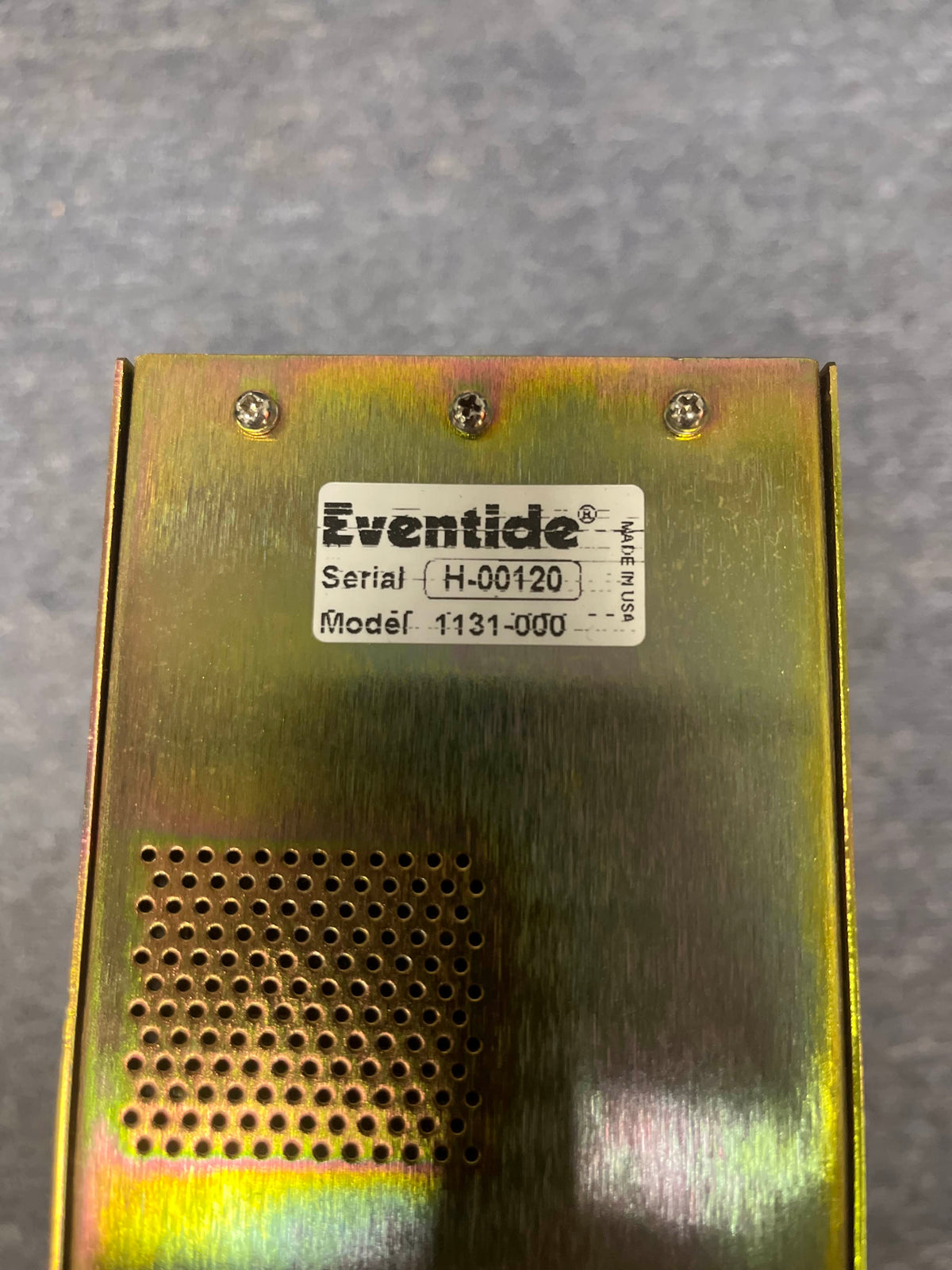 Close-up of a metallic Eventide H8000 Multi-Channel Effects System (Preowned) shows its label, serial number H-00120, model 1131-000, along with four screws and a vent grid on this harmonizer and multi-effects processor.