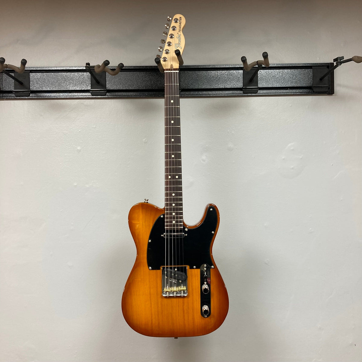 Fender American Performer Telecaster Honeyburst on a hook, showcasing its black neck and rosewood fingerboard.