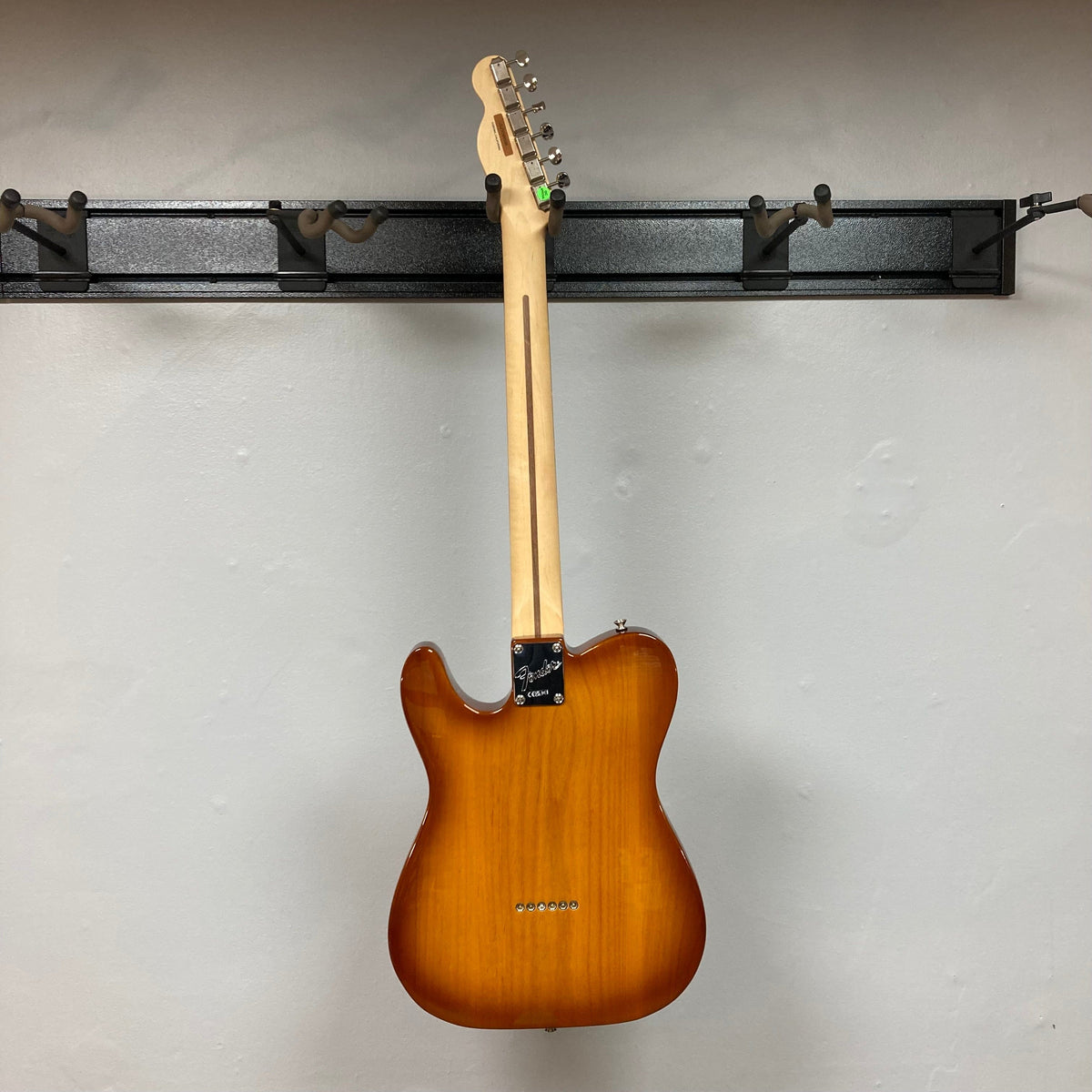Fender American Performer Telecaster Honeyburst guitar on a wall hook, showcasing its body and neck with ClassicGear tuners and Yosemite pickups.