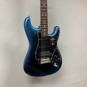 A Fender American Professional II Stratocaster HSS in Dark Night with chrome hardware and a black pickguard hangs on a light gray wall.