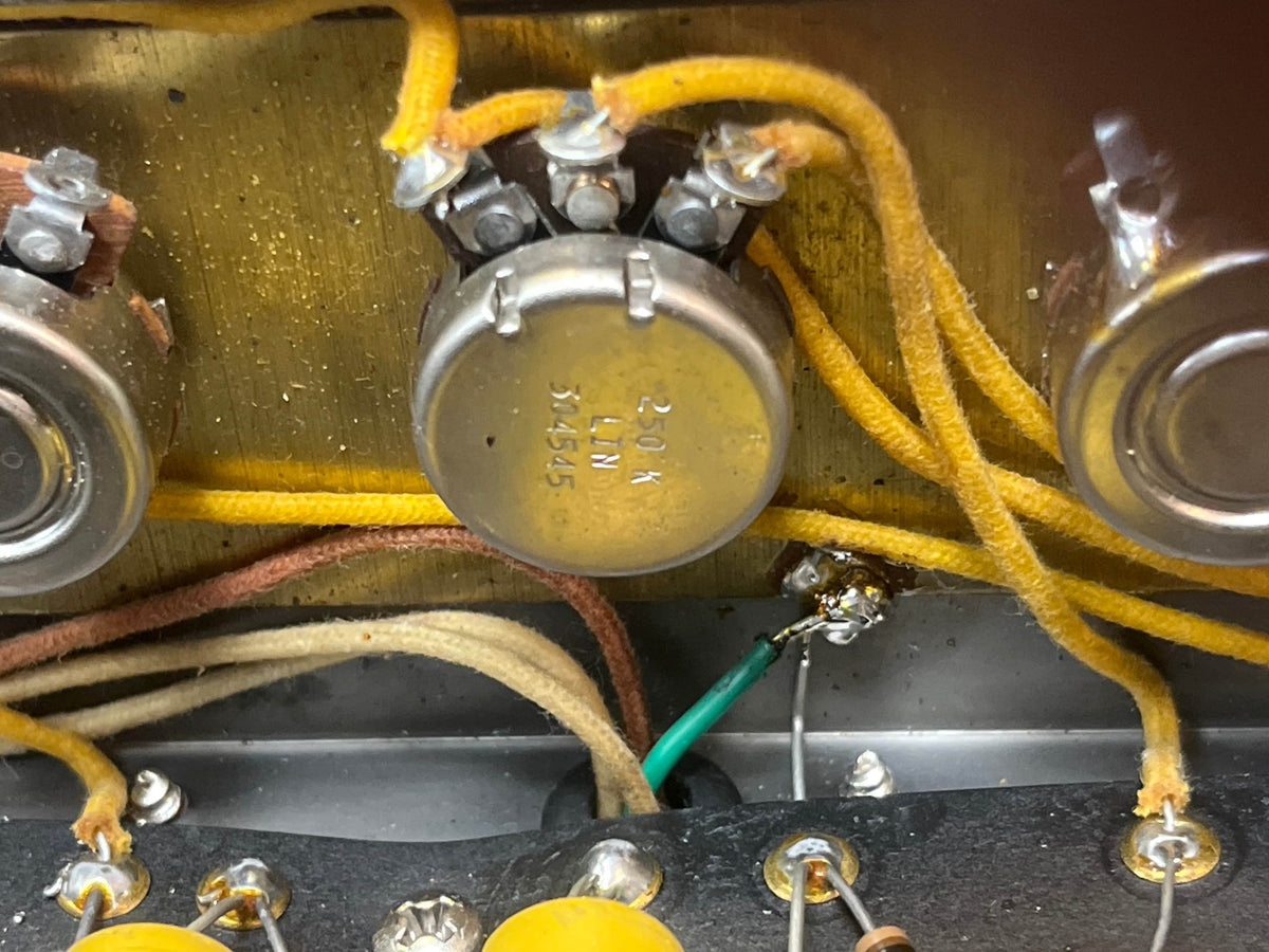 Close-up of vintage electronic parts—20K potentiometer, resistors, and cloth-covered wires—inside a metal enclosure from a 1957 Fender Bassman 5F6 Narrow Panel 40-Watt 4x10" Guitar Combo w/Flight Case.