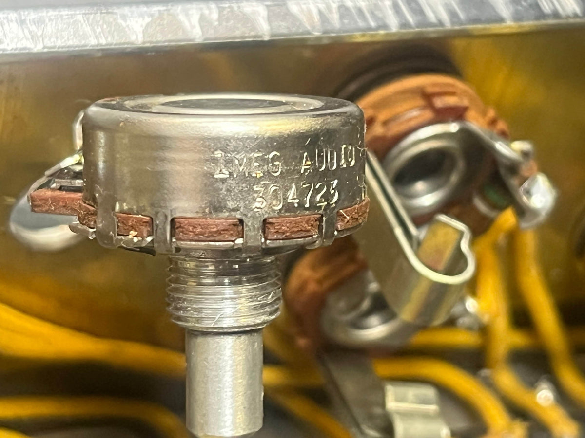Close-up of a metal rotary potentiometer with serial numbers and brown wiring, mounted on a Fender 1957 Bassman 5F6 Narrow Panel 40-Watt 4x10" Guitar Combo; yellow wires and metal parts are visible in the background.