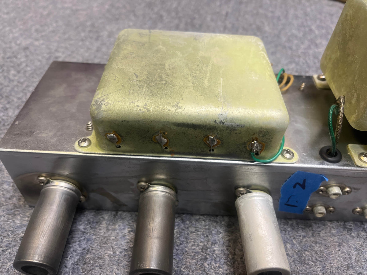 Fender metal component with a yellowish cover, attached wires, and four cylindrical connectors—like those in the 1957 Fender Bassman 5F6 Narrow Panel 40-Watt 4x10" Guitar Combo w/Flight Case—plus a blue tape label marked "7".