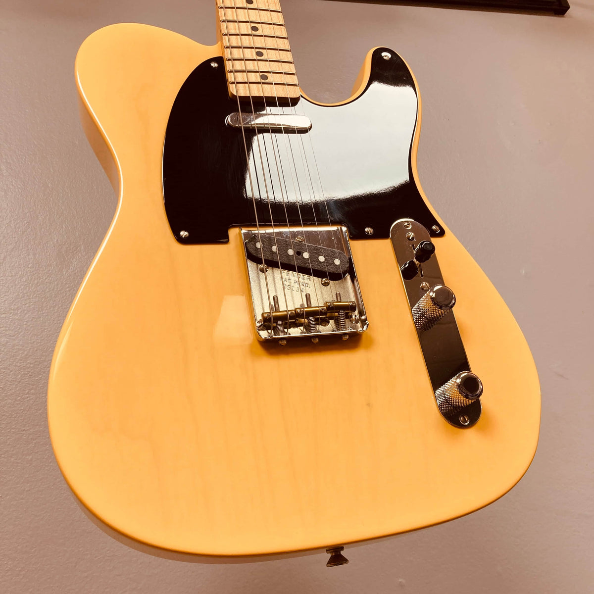 A close-up of a yellow Fender Custom Shop '51 Reissue Nocaster NOS 2006 electric guitar, featuring a black pickguard, metal bridge, and control knobs against a plain background.