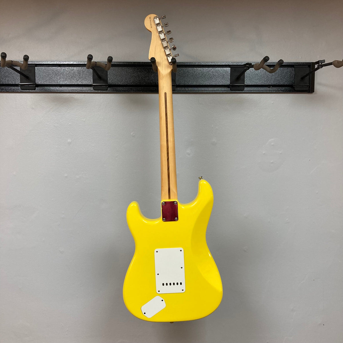 Fender Deluxe Powerhouse Stratocaster MIM Rare Graffitti Yellow electric guitar with vintage and modern features, displayed on a wall.