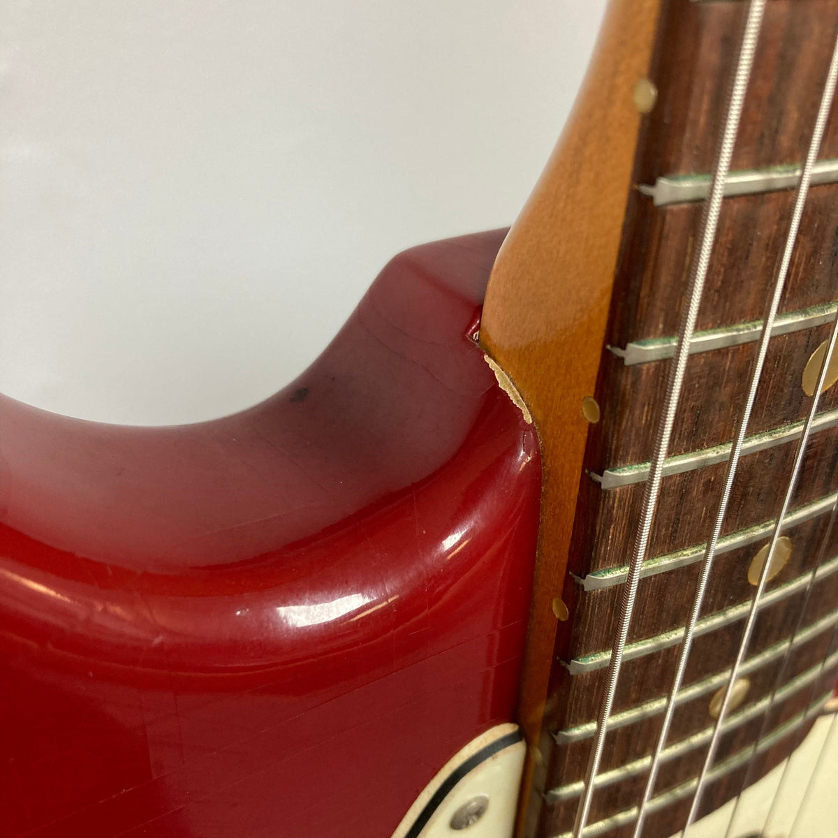 Close-up of a Fender Duo-Sonic II Dakota Red 1966 vintage guitar neck and body with minor blemishes and heavy finish checking.